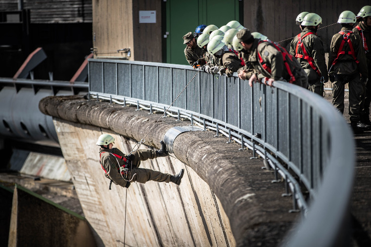 Soldat der sich von einer Brücke abseilt